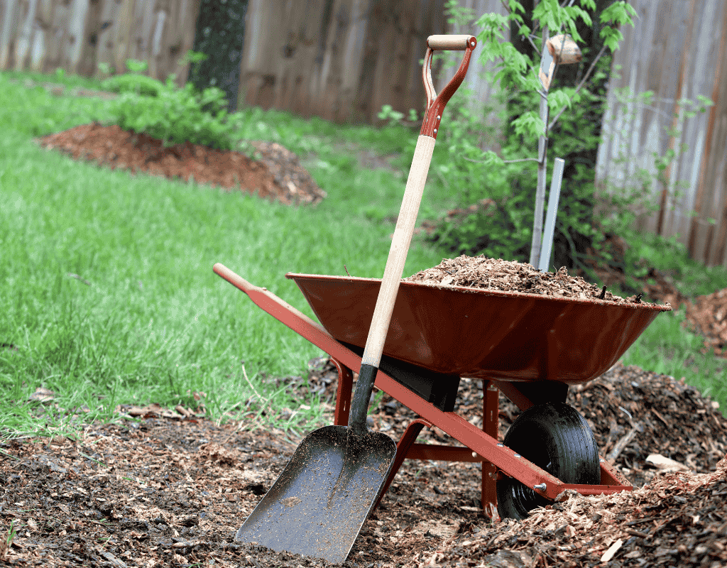 Landscaping tools and mulch used for garden bed installation in residential landscape project
