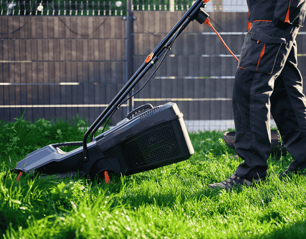 Lawn care professional mowing residential yard with push mower during routine lawn maintenance