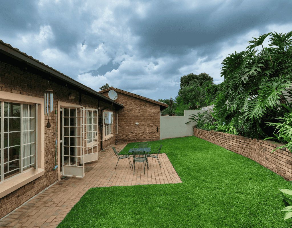 Residential backyard patio and outdoor living area with landscaped lawn and garden