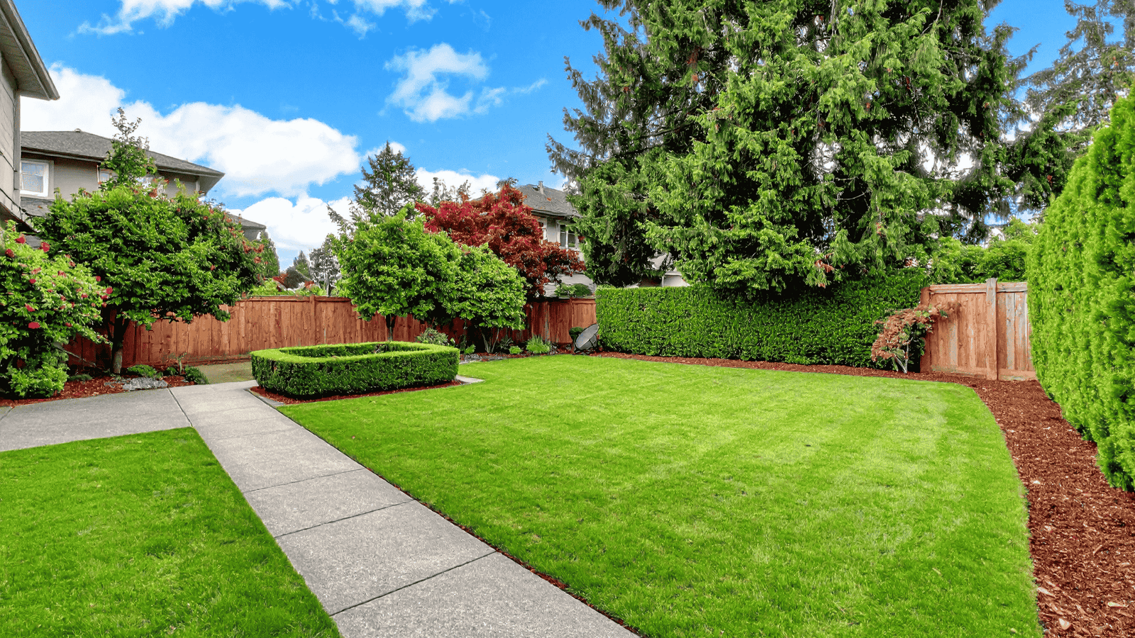 Outdoor garden landscape with stone pathway, flowers, and sprinkler irrigation system