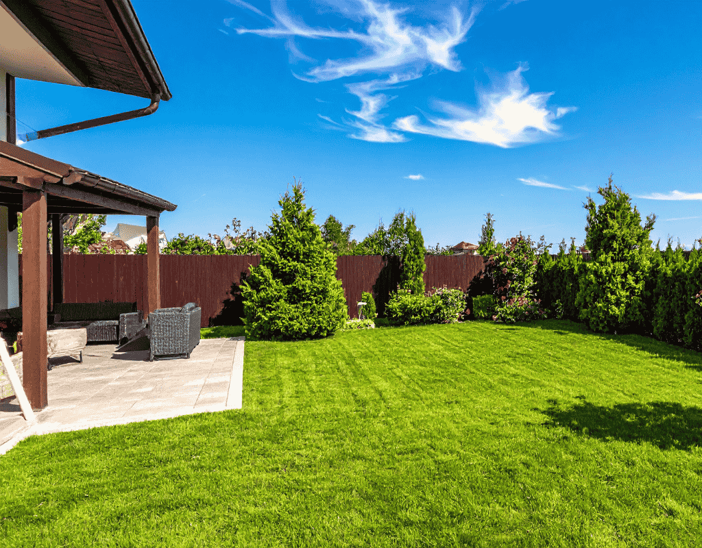 Beautiful landscaped backyard with green lawn and outdoor seating area for outdoor living space